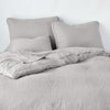 Austin Sham | Fog | Midweight linen shams shown from foot of bed, leaning against a plain background with monochromatic bedding.