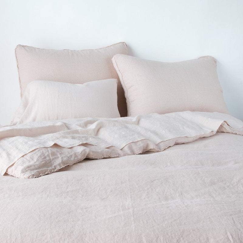 Austin Sham | Pearl | Midweight linen shams shown from foot of bed, leaning against a plain background with monochromatic bedding.
