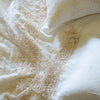 Frida Pillowcase (Single) | Close up of a Frida flat sheet and pillowcase, layered over embroidered silk velvet, all in winter white - overhead view.