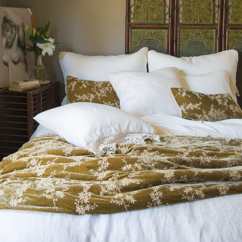 Linen duvet cover in white layered under white frida lace sheeting and sleeping pillows and rich honeycomb silk velvet accessory pieces - end of bed view.
