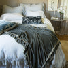 Linen Whisper Duvet Cover | Linen Whisper bed duvet cover in mineral, layered with a matching bed skirt and richly colored silk velvet accessory pieces - end of bed view.