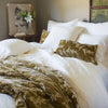 Lynette Blanket | Honeycomb Lynette throw blanket and accent pillows add rich color to a white bed of linen and cotton lace - close-up end of bed view.