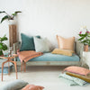 Ines Throw Pillow | Cloud | Ines 24 by 24 pillow on an soft blue antique day bed, layered with accessory pieces in pink, blue, and green tones in linen and charmeuse. Styled with copper accents and greenery.