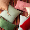 Ines Throw Pillow | Ines, silk charmeuse, and silk velvet throw pillows in pink and green tones, scattered on a boldly striped rug - overhead view.