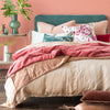 Pale nude pink Paloma Duvet cover layered under light, mid, and dark tone pinks and eucalyptus green - end of bed view.
