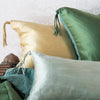 Close-up of three Taline throw pillows in green and gold tones, showcasing the corner tassel details.