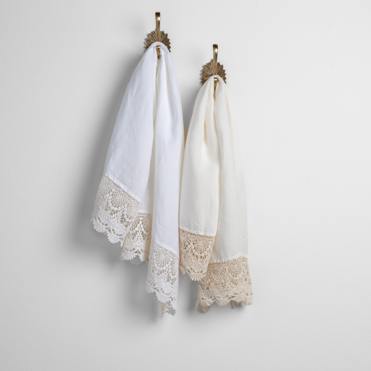 Mattine Guest Towel | two linen with lace guest towels in white and winter white on decorative towel hooks mounted on a white wall. 