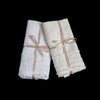 Austin Guest Towel | white and winter white midweight linen guest towels tied with ribbons against a black background.