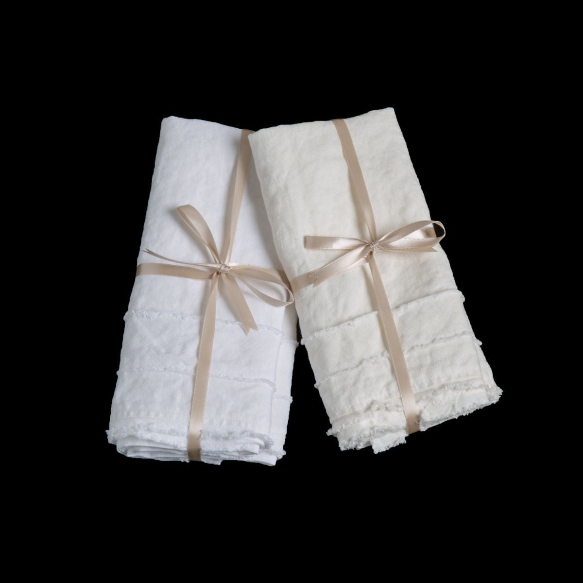Austin Guest Towel | white and winter white midweight linen guest towels tied with ribbons against a black background.