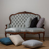Austin Throw Pillow | midweight linen throw pillows in various colors scattered on an antique sofa and medium wood floor.