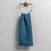Austin Guest Towel | Cenote | midweight linen guest towel with raw edge band at both ends hanging from a towel ring mounted to a white wall.