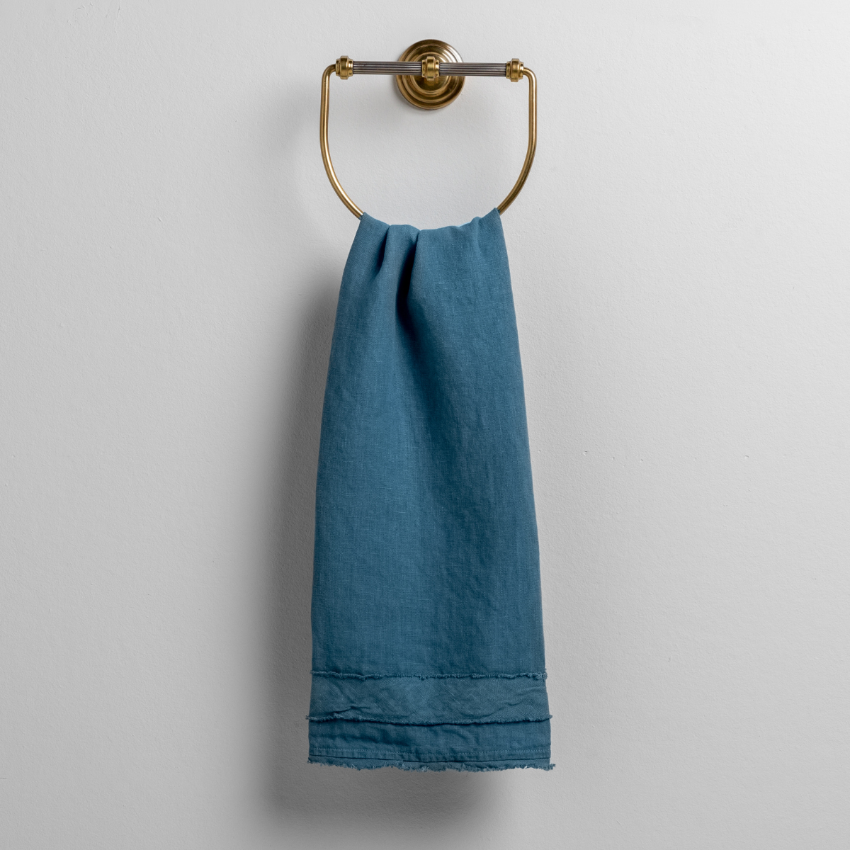 Austin Guest Towel | Cenote | midweight linen guest towel with raw edge band at both ends hanging from a towel ring mounted to a white wall.