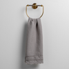 Austin Guest Towel | Fog | midweight linen guest towel with raw edge band at both ends hanging from a towel ring mounted to a white wall.
