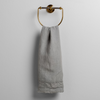 Austin Guest Towel | Mineral | midweight linen guest towel with raw edge band at both ends hanging from a towel ring mounted to a white wall.