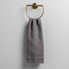 Austin Guest Towel | Moonlight | midweight linen guest towel with raw edge band at both ends hanging from a towel ring mounted to a white wall.