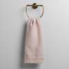 Austin Guest Towel | Pearl | midweight linen guest towel with raw edge band at both ends hanging from a towel ring mounted to a white wall.