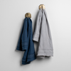 Austin Guest Towel | pair of midweight linen guest towels in midnight and minderal on gold hooks against a white wall.