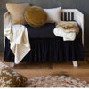 Harlow Crib Skirt | black crib skirt and crib sheet on a neutral crib with neutral and golden toned blankets and throw pillows.
