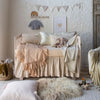 Harlow Crib Skirt | a neutral crib styled with neutral tones in a nursery scene with adornments on the wall and toys and stuffed animals placed throuughout the scene.