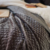 Close-up of Silk velvet quilted coverlet in moonlight, rumpled and pulled back to showcase the satin back.