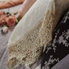 Frida Pillowcase (Single) | Close up of parchment Frida pillowcase over moonlight bedding, highlighting antique cotton lace detail - side view.