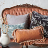 Loulah Throw Pillow | Loulah Accent pillow in rouge, layered against grey and blue tones on a vintage loveseat.