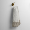 Mattine Guest Towel | Cloud | linen with mattine lace trimmed guest towel on a decorative towel ring mounted on a white wall.