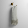 Mattine Guest Towel | Eucalyptus | linen with mattine lace trimmed guest towel on a decorative towel ring mounted on a white wall.