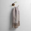 Mattine Guest Towel | Fog | linen with mattine lace trimmed guest towel on a decorative towel ring mounted on a white wall.