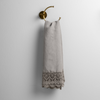 Mattine Guest Towel | Mineral linen with mattine lace trimmed guest towel on a decorative towel ring mounted on a white wall. 