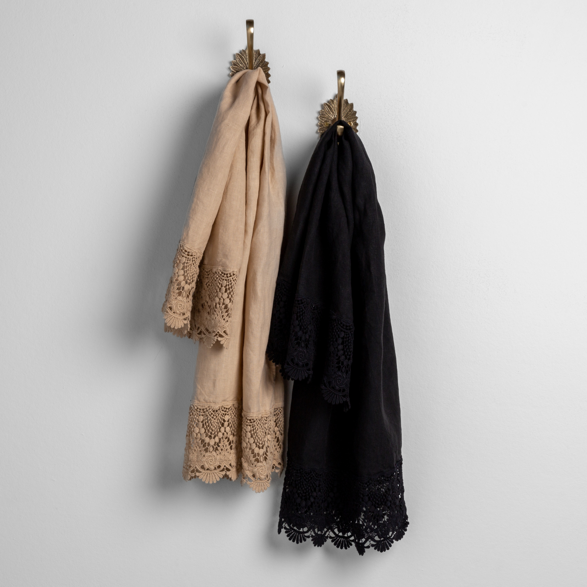 Mattine Guest Towel | lace trimmed linen guest towels in honeycomb and corvino hanging from decorative towel hooks against a plain white wall. 