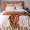 Paloma shams and matching bed skirt add subtle shine to linen and cotton bedding accented with ruffled silk velvet, all in pink and cream tones - end of bed view.