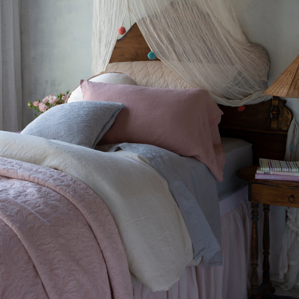 Adele Twin Coverlet | Coverlet in pearl layered with cream and soft blue tones in linen and quilted charmeuse under a gauzy canopy - angled view.