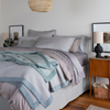 Cirillo Blanket | king-sized bed dressed in cotton sateen, both quilted and unquilted - the blanket is rumpled and layered on a coverlet and duvet cover.