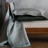 Cirillo Blanket | throw blanket and throw pillows in quilted cotton sateen shown on the end of a daybed - the pillows are stacked and the blanket draped over the side.