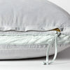 Harlow Sham | Close-up of charmeuse gusset, raw-edge trim, and brass zipper detail  on cloud Harlow pillow - cloud, side view.
