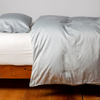 Bria Twin Duvet Cover | Cloud | duvet cover and matching sleeping pillow on white sheeting - side view.