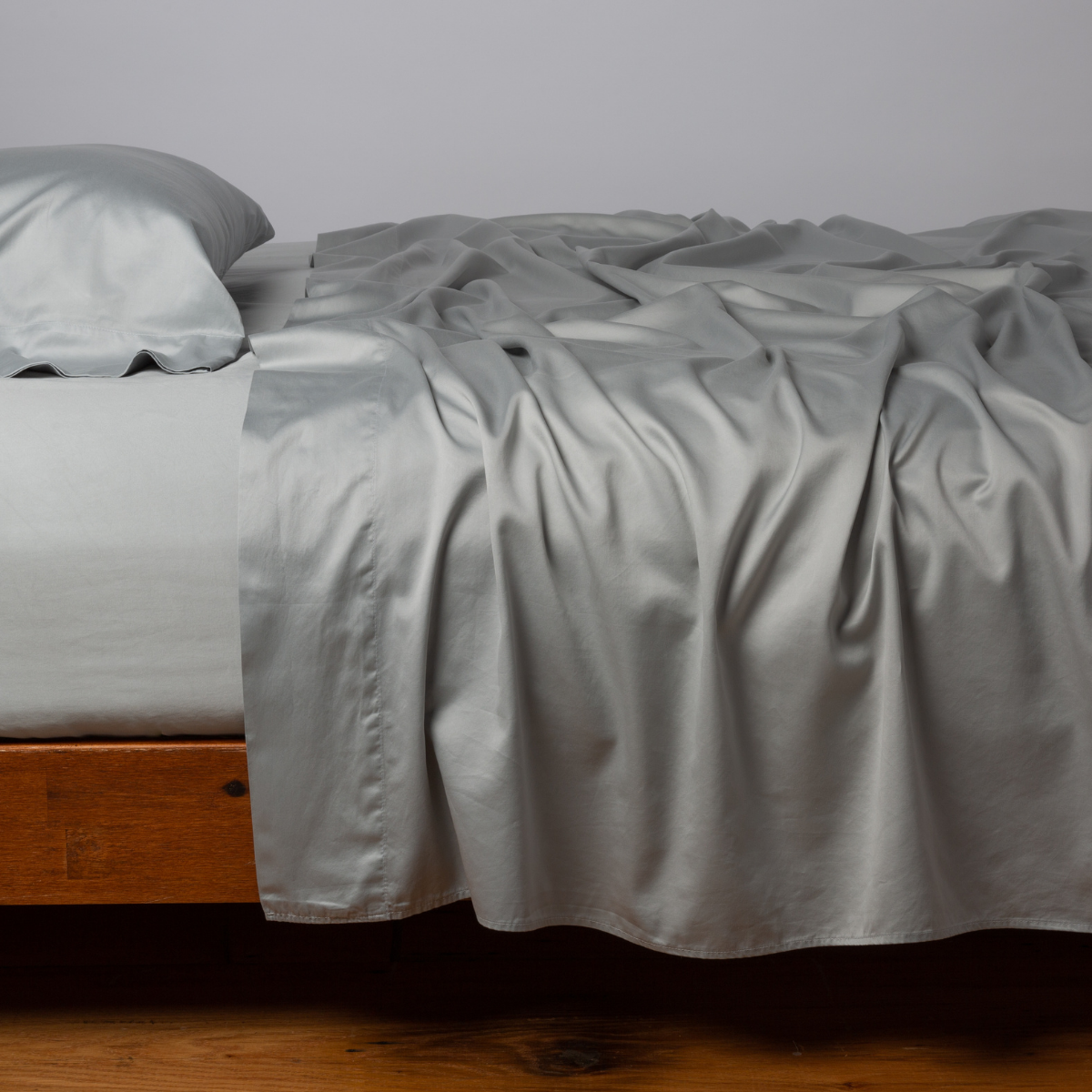 Bria Fitted Sheet | Mineral | Cotton sateen fitted sheet shown with matching flat sheet and sleeping pillow - side view.