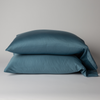 Bria Standard Pillowcase (Single) | Cenote | Two cotton sateen sleeping pillows, stacked neatly against a white backdrop - side view.