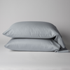 Bria Standard Pillowcase (Single) | Cloud | Two cotton sateen sleeping pillows, stacked neatly against a white backdrop - side view.