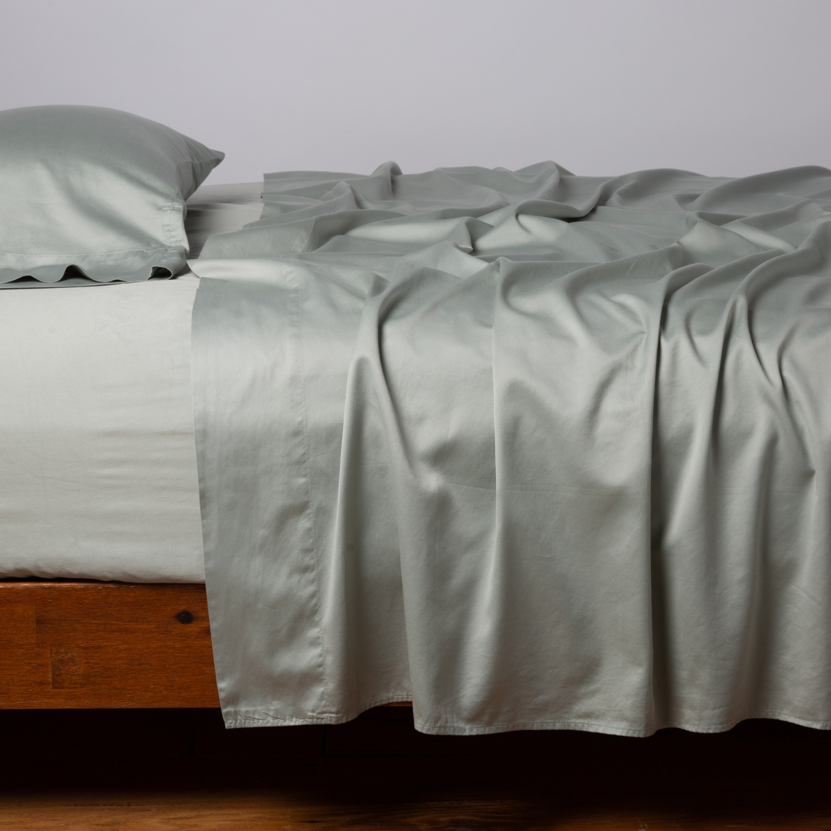 Bria Standard Pillowcase (Single) | Eucalyptus | Cotton sateen sleeping pillow, on a bed with matching sheets - side view.