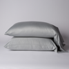 Bria Standard Pillowcase (Single) | Mineral | Two cotton sateen sleeping pillows, stacked neatly against a white backdrop - side view.