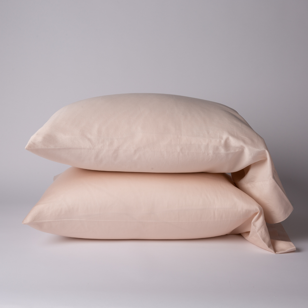 Bria Pillowcase (Single) | Pearl | Two cotton sateen sleeping pillows, stacked neatly against a white backdrop - side view.