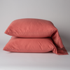 Bria Standard Pillowcase (Single) | Poppy | Two cotton sateen sleeping pillows, stacked neatly against a white backdrop - side view.