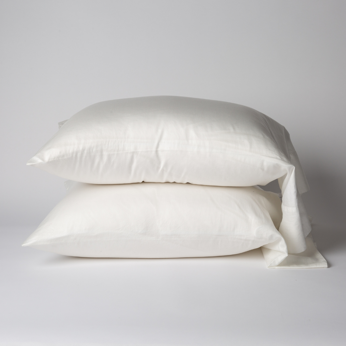 Bria Standard Pillowcase (Single) | Winter White | Two cotton sateen sleeping pillows, stacked neatly against a white backdrop - side view.