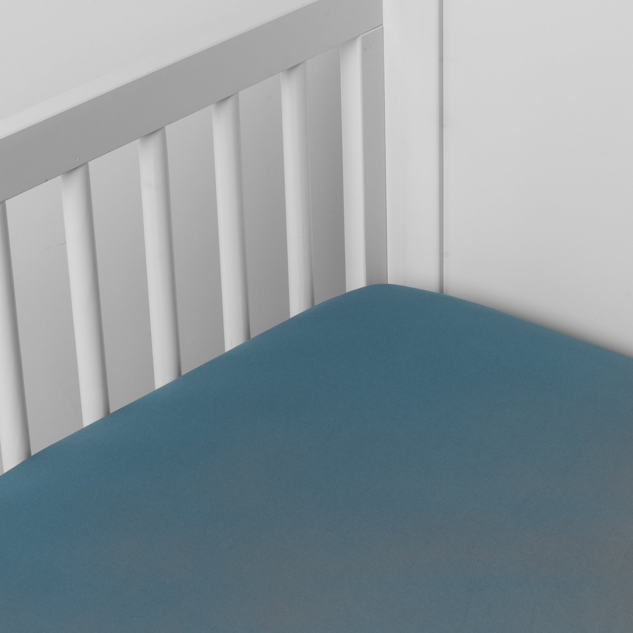 Bria Crib Sheet | Cenote | Cotton sateen crib sheet shown from a slight overhead angle into  an inside corner of a crib.