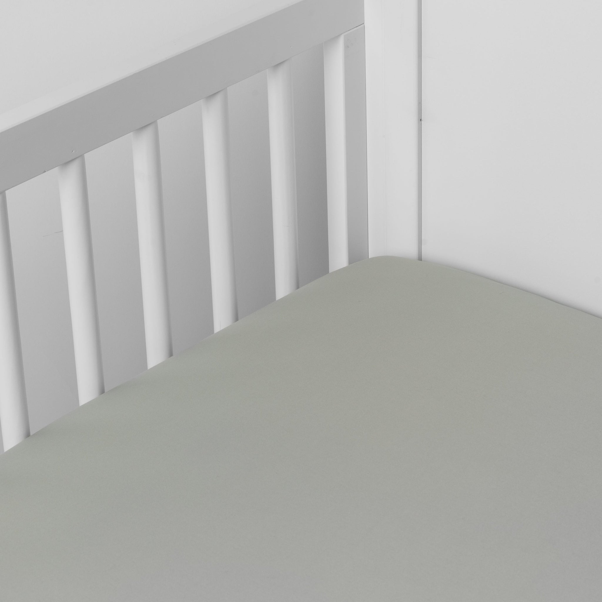 Bria Crib Sheet | Eucalyptus | Cotton sateen crib sheet shown from a slight overhead angle into  an inside corner of a crib.