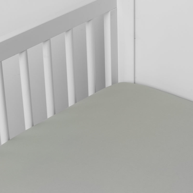 Bria Crib Sheet | Eucalyptus | Cotton sateen crib sheet shown from a slight overhead angle into  an inside corner of a crib.