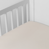 Bria Crib Sheet | Parchment | Cotton sateen crib sheet shown from a slight overhead angle into  an inside corner of a crib.