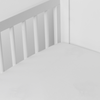 Bria Crib Sheet | Winter White | Cotton sateen crib sheet shown from a slight overhead angle into  an inside corner of a crib.